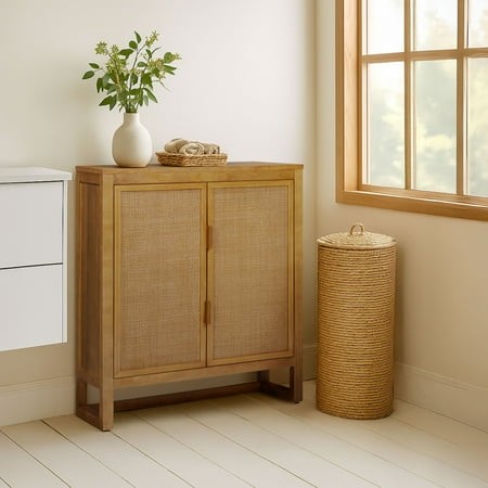 Natural wood accent cabinet featuring two doors with woven rattan panels, adjustable shelves inside, and a minimalist design, placed next to a window with a vase of flowers.