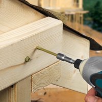 Green hex head timber screw being drilled into wood, showing TIMCO 150INDEXP exterior screw in use.