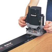 Black Trend Contractor One Piece Hinge Jig with adjustable metal guide and ruler markings, held by a person.