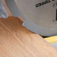 Circular saw blade with six teeth, silver finish, mounted on a saw cutting through wood.
