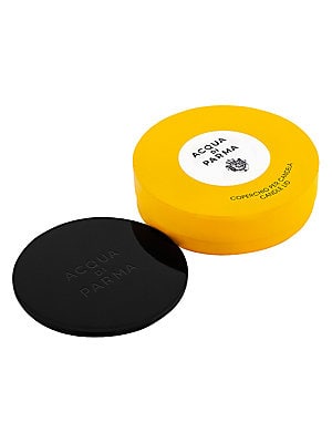 Black candle lid with a smooth finish, featuring embossed "Acqua Di Parma" text, placed atop a vibrant yellow circular box with a white label.
