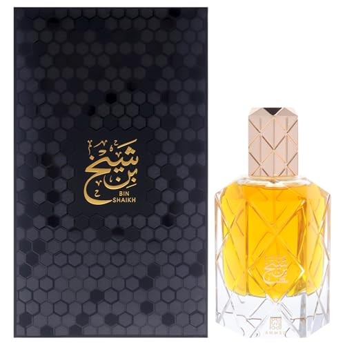 Elegant hexagonal bottle with a golden-yellow fragrance, topped with a decorative rose gold cap, presented in a sleek black box featuring gold Arabic calligraphy.