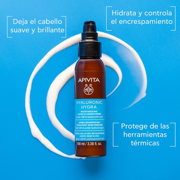 Brown spray bottle with a black pump, labeled "APIVITA HYALURONIC HYDRA," containing a white, creamy conditioner, set against a bright blue background.