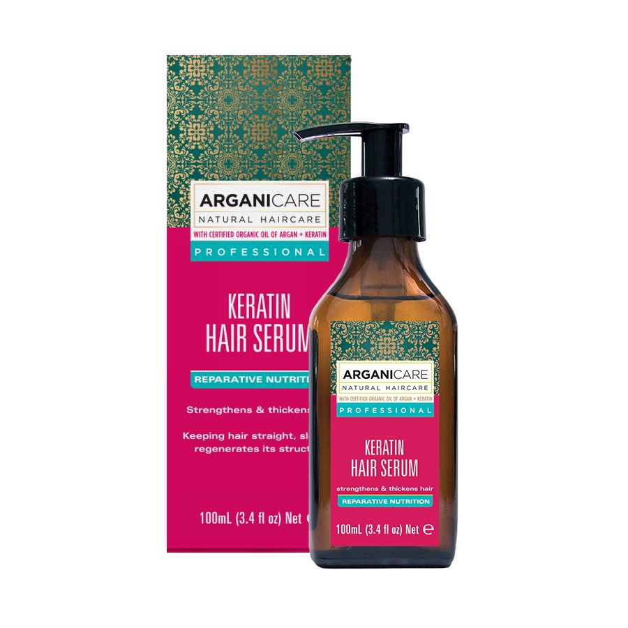 Brown glass bottle with a black pump, labeled "ARGANICARE Keratin Hair Serum," surrounded by a vibrant pink and green box featuring ornate patterns, highlighting its nourishing properties.