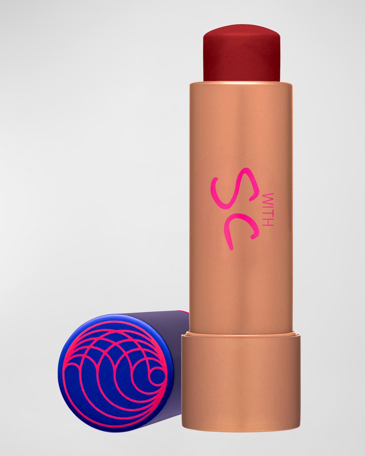 Tinted balm in a sleek, rose gold tube with a vibrant red tip, featuring a blue and purple cap adorned with a spiral design, labeled with "SC" in pink.