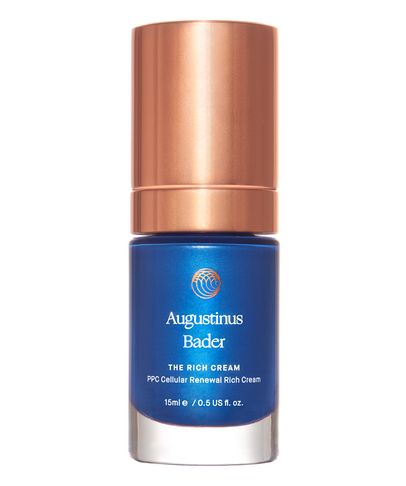 The Rich Cream by Augustinus Bader in a 15ml blue glass bottle with a sleek design, featuring a gold cap and the brand's logo prominently displayed.
