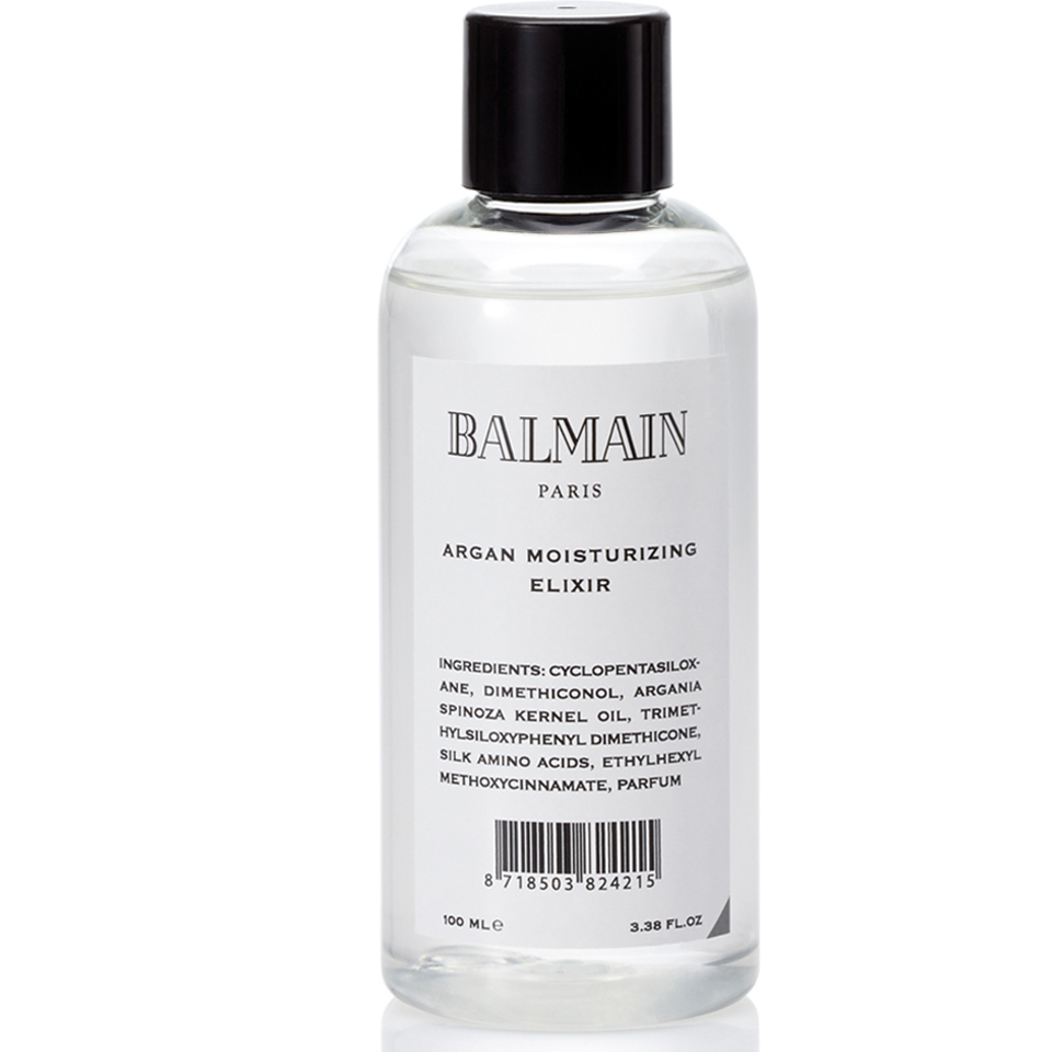 Clear glass bottle containing 100ml of Balmain Argan Moisturizing Elixir, featuring a black and white label with "BALMAIN PARIS" and product details.
