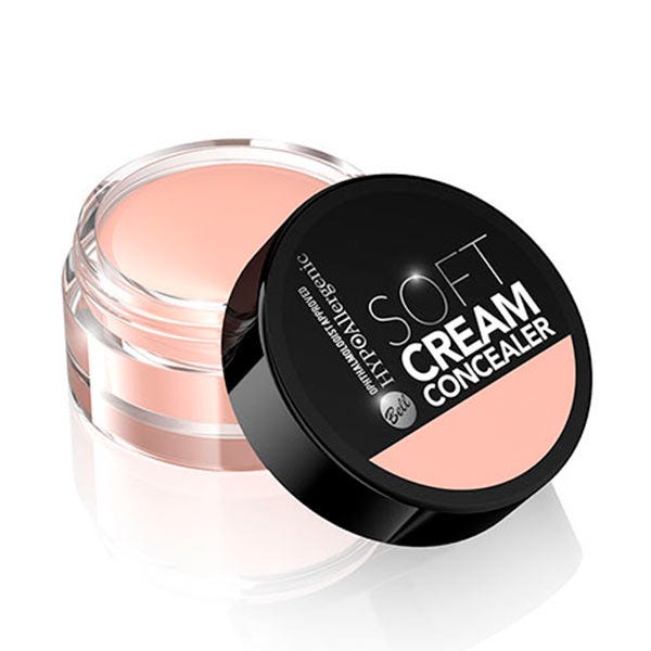 Light peach cream concealer in a round, clear jar with a black lid, labeled "Soft Cream Concealer" by Bell, showcasing a smooth, creamy texture.
