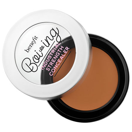 Round compact featuring Benefit Cosmetics Boi-Ing Industrial Strength Full Coverage Concealer in Deep Warm, with a shiny silver lid and a dark brown creamy product inside.