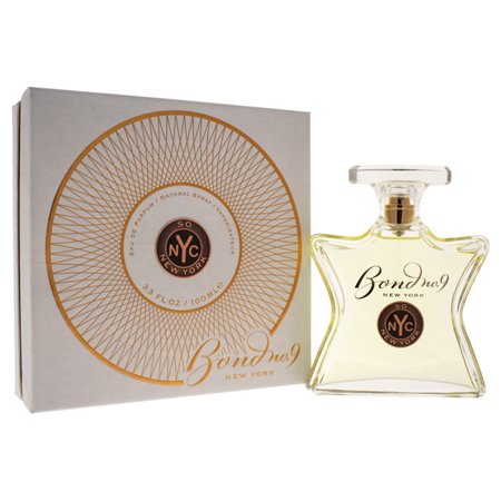 Clear glass bottle with a star shape, featuring a gold cap and a circular label with "Bond No 9" and "So New York," accompanied by a decorative box with a geometric gold design.