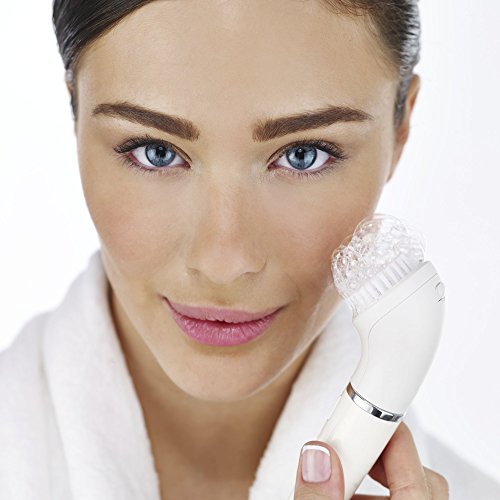 The Braun FaceSpa 810 is a white facial cleansing device featuring a rounded brush head, held by a woman with smooth skin, wearing a white robe, showcasing its sleek design.