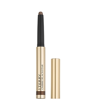A gold and black twist-up eyeshadow stick with the label "By Terry Ombre Blackstar" prominently displayed, featuring a rich, deep brown color.