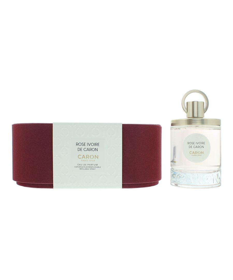Elegant glass bottle of Caron Rose Ivoire EDP, 100 ml, with a silver cap, beside a deep red cylindrical box featuring a light blue label.