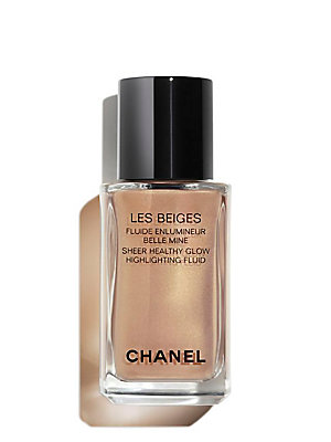 Transparent glass bottle with a sleek black cap, containing a sheer, golden liquid labeled "LES BEIGES HIGHLIGHTING FLUID" by CHANEL for a luminous glow.