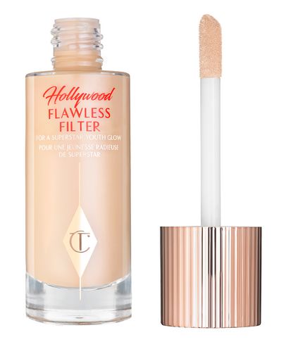 Charlotte Tilbury Hollywood Flawless Filter in 2 Fair, featuring a glass bottle with a rose gold cap and a doe-foot applicator, offers a lightweight, radiant primer for a youthful glow.