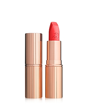 Bright coral pink lipstick in a sleek, rose gold tube with ribbed detailing, featuring a unique angled tip and embossed logo on the bullet.