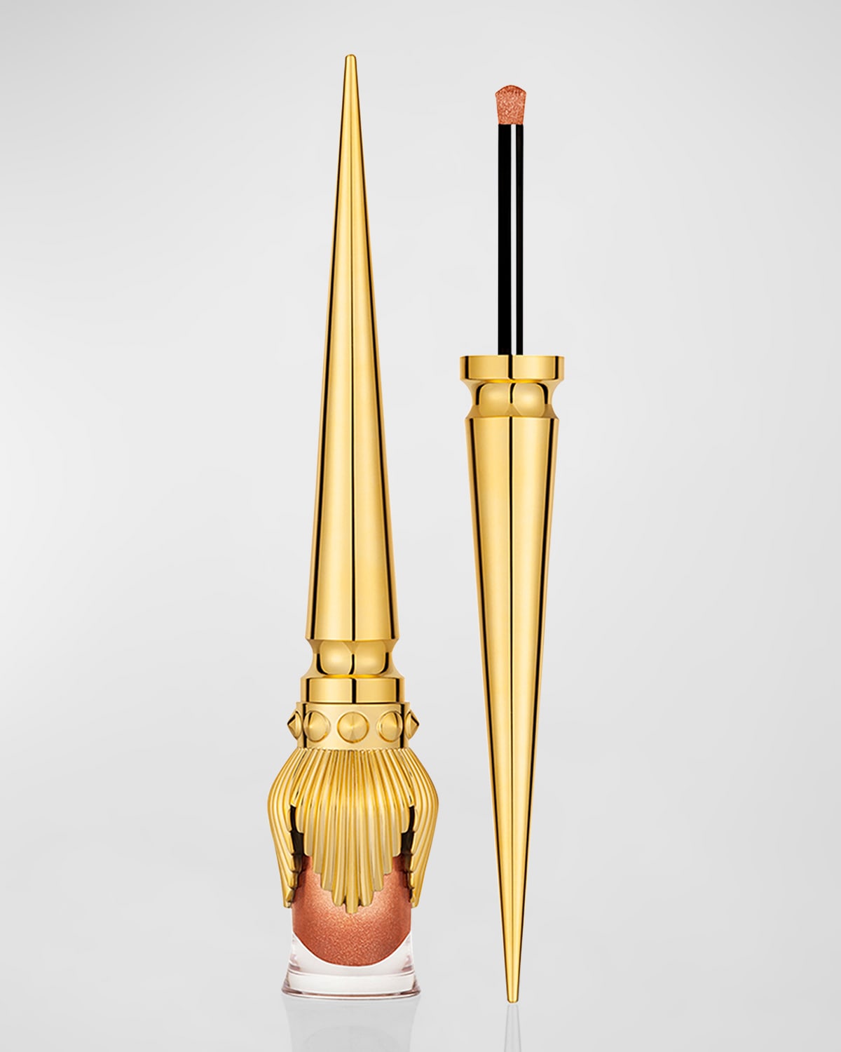 Christian Louboutin Tape à L'Oeil Liquid Eyeshadow in Topaze features a luxurious gold bottle with a spiked top and a slender applicator, showcasing a shimmering copper hue.