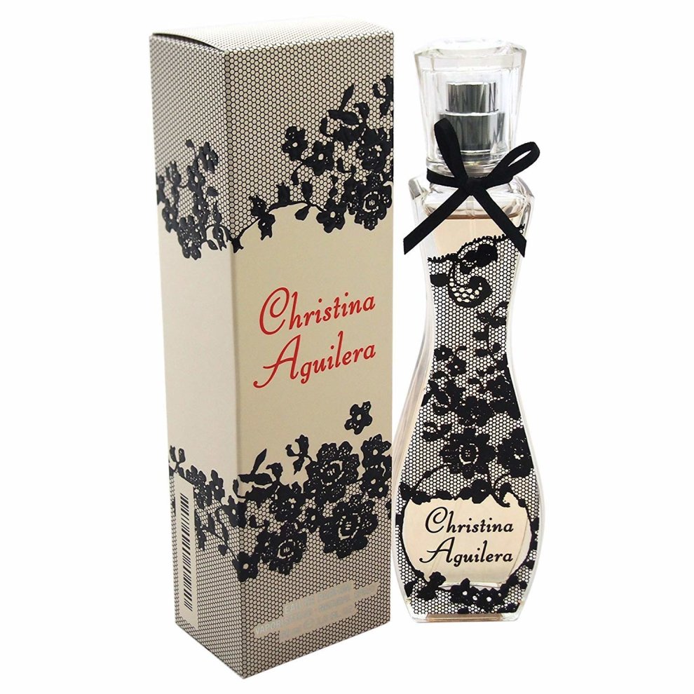 Clear glass perfume bottle with a floral design, topped with a silver cap and a black bow, displayed next to a patterned box featuring black and white flowers.