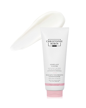 Delicate volumizing conditioner in a white tube with a pink label, featuring a creamy texture spilling out, designed for enhancing hair volume and softness.