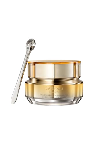 Gold and clear glass jar of Clé de Peau Beauté Eye Contour Cream Supreme with a silver applicator spoon, featuring a sleek, modern design.
