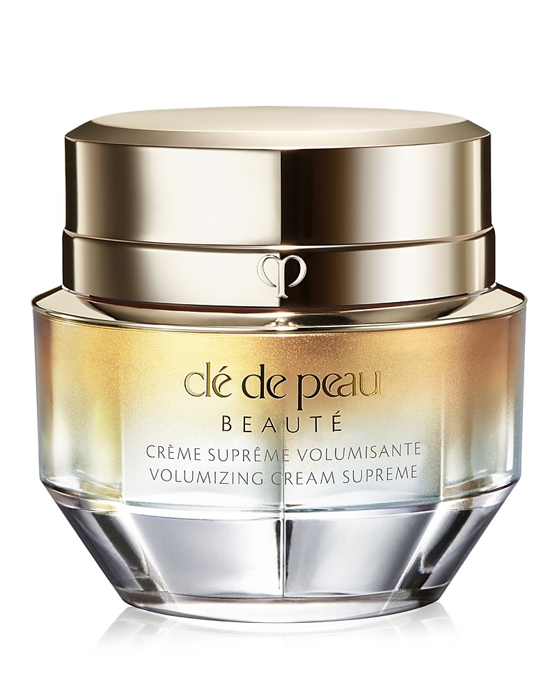 Clé De Peau Beauté Volumizing Cream Supreme in a luxurious glass jar with a gold lid, featuring a gradient design from gold to clear, labeled prominently on the front.