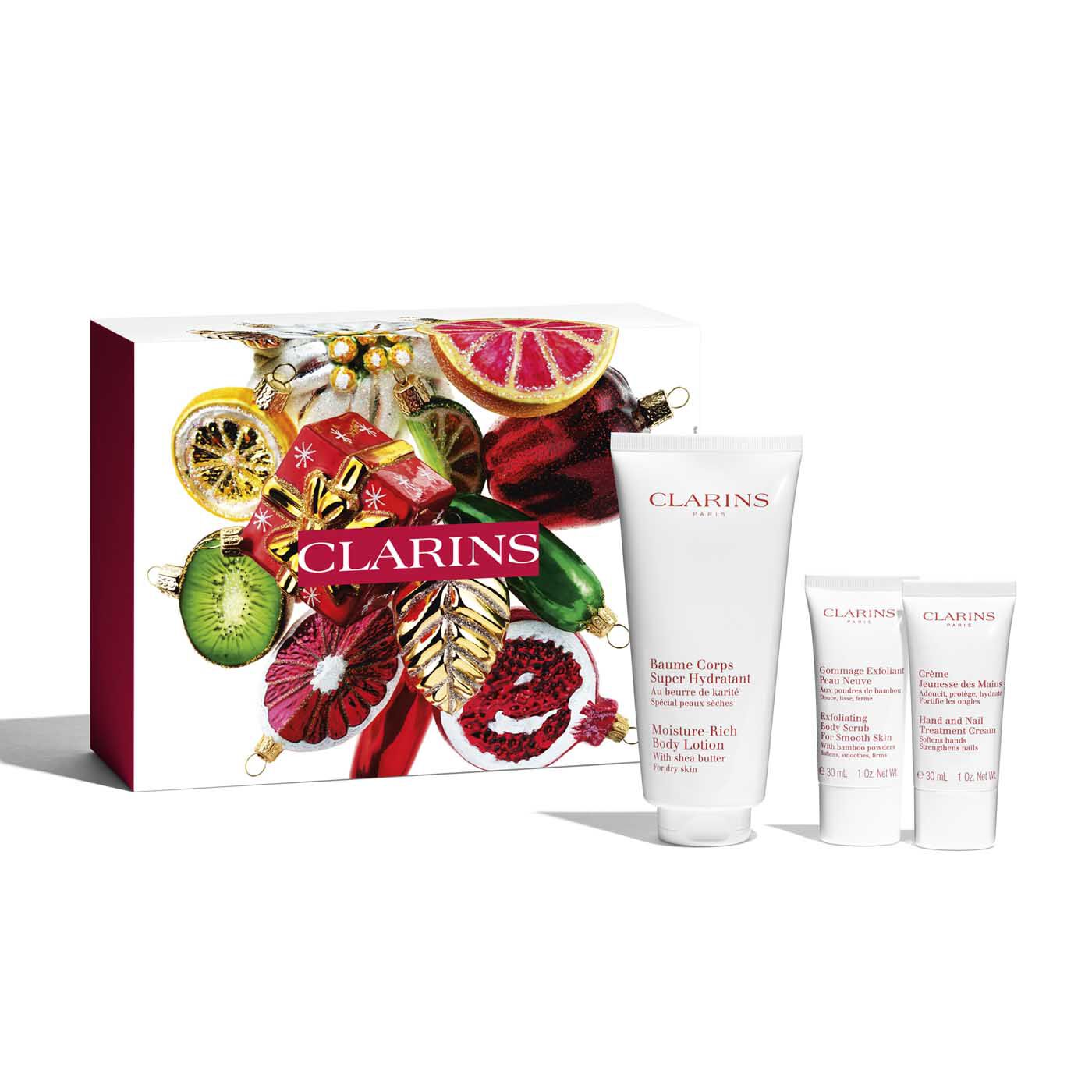 Clarins Moisture-Rich 4 Piece Gift Set featuring a white body lotion tube, two small treatment tubes, and a festive red and white gift box adorned with colorful fruits and holiday decorations.