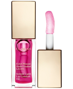 Clarins Instant Light Lip Comfort Oil in Raspberry features a sleek glass bottle with a gold cap, showcasing a vibrant pink oil and a soft applicator wand.