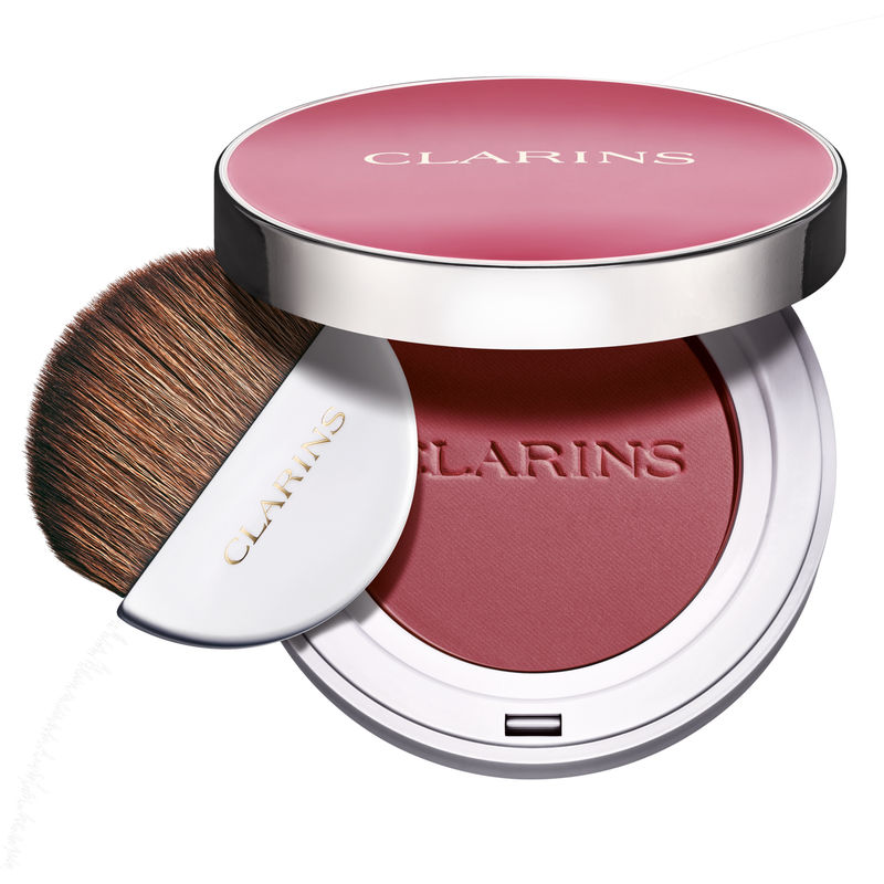 Clarins Joli Blush in 04 Cheeky Purple features a round compact with a silver rim, a soft pink blush, and a small brush tucked into the lid for easy application.