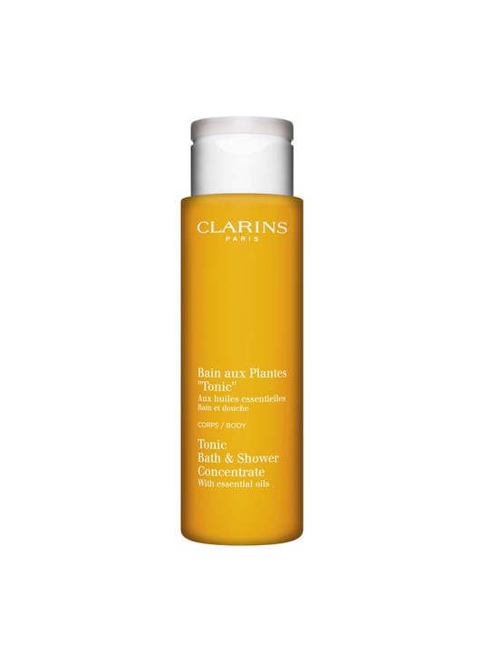 Yellow cylindrical bottle of Clarins Tonic Bath & Shower Concentrate, labeled in white text, featuring essential oils, with a white cap, 6.8 ounces.