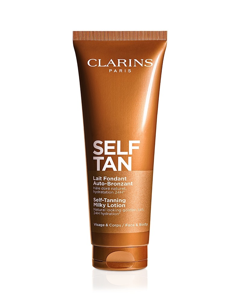 Clarins Self-Tan Milky Lotion in a brown tube with a flip-top cap, featuring white text and gold accents, designed for face and body tanning, 4.5 oz size.