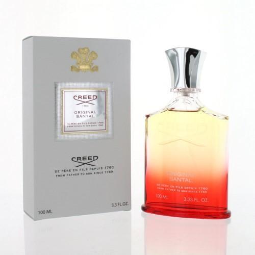 Clear glass bottle with an ombre effect from amber to clear, featuring a silver cap, alongside a gray box with a decorative label and gold crest, both labeled "Creed Original Santal."