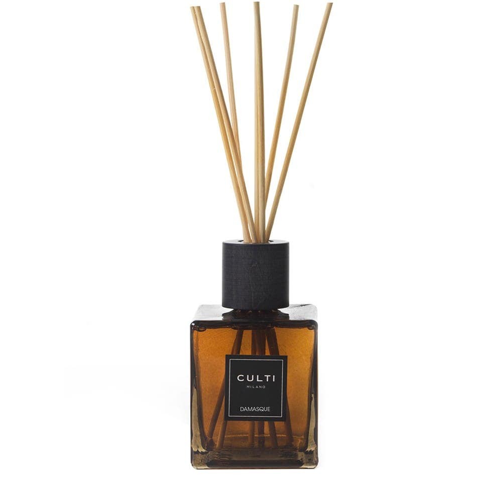 Square glass diffuser in amber with a black wooden cap, featuring five reed sticks, labeled "CULTI Damasque," exuding an elegant and classic design.