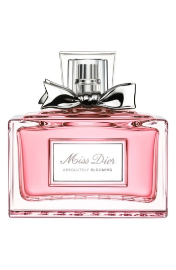 Clear glass bottle with a pink liquid, featuring a silver cap and a black ribbon bow around the neck, labeled "Miss Dior Absolutely Blooming."