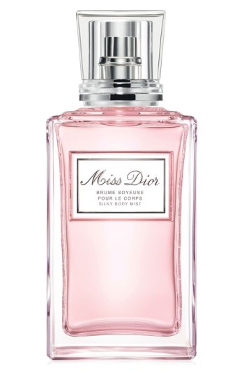 Clear glass bottle with a rectangular shape, featuring a silver cap and a label that reads "Miss Dior," containing a light pink body mist.