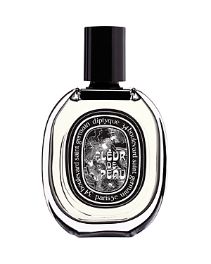 Clear glass perfume bottle with an oval shape, featuring a black cap and a decorative label that reads "Fleur De Peau" in elegant font, set against a white background.
