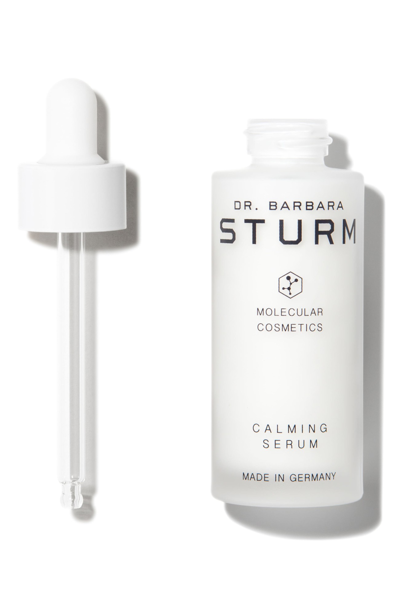 Clear glass bottle with a white dropper cap, labeled "Dr. Barbara Sturm Calming Serum," featuring minimalist black text and a hexagonal logo, made in Germany.