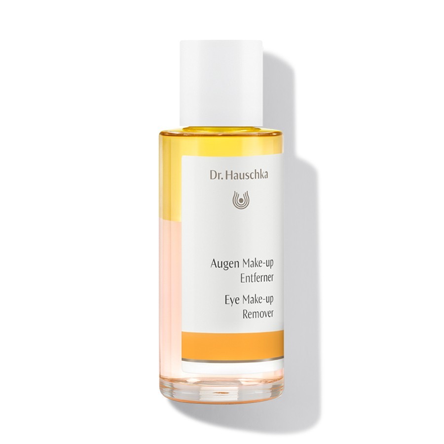 Dr. Hauschka Eye Makeup Remover in a clear glass bottle, featuring a bi-phase formula with a yellow oil layer and a clear liquid layer, topped with a white cap and labeled in black text.