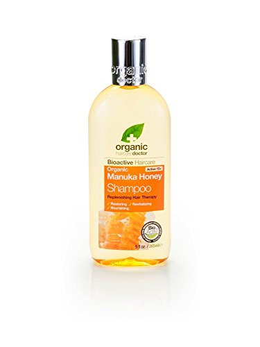 Clear bottle of Dr Organic Manuka Honey Shampoo, featuring a yellow-orange liquid, green leaf logo, and orange label with text highlighting its organic and nourishing properties.