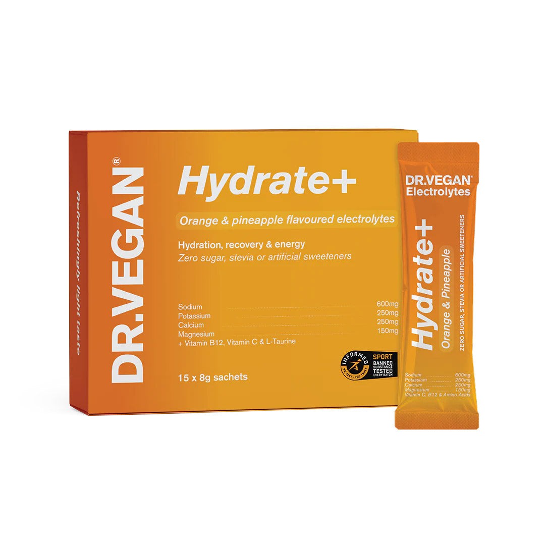 Bright orange box labeled "DR. VEGAN Hydrate+ Orange & Pineapple," containing 15 sachets, with a single sachet displayed, featuring vibrant colors and key nutrient details.
