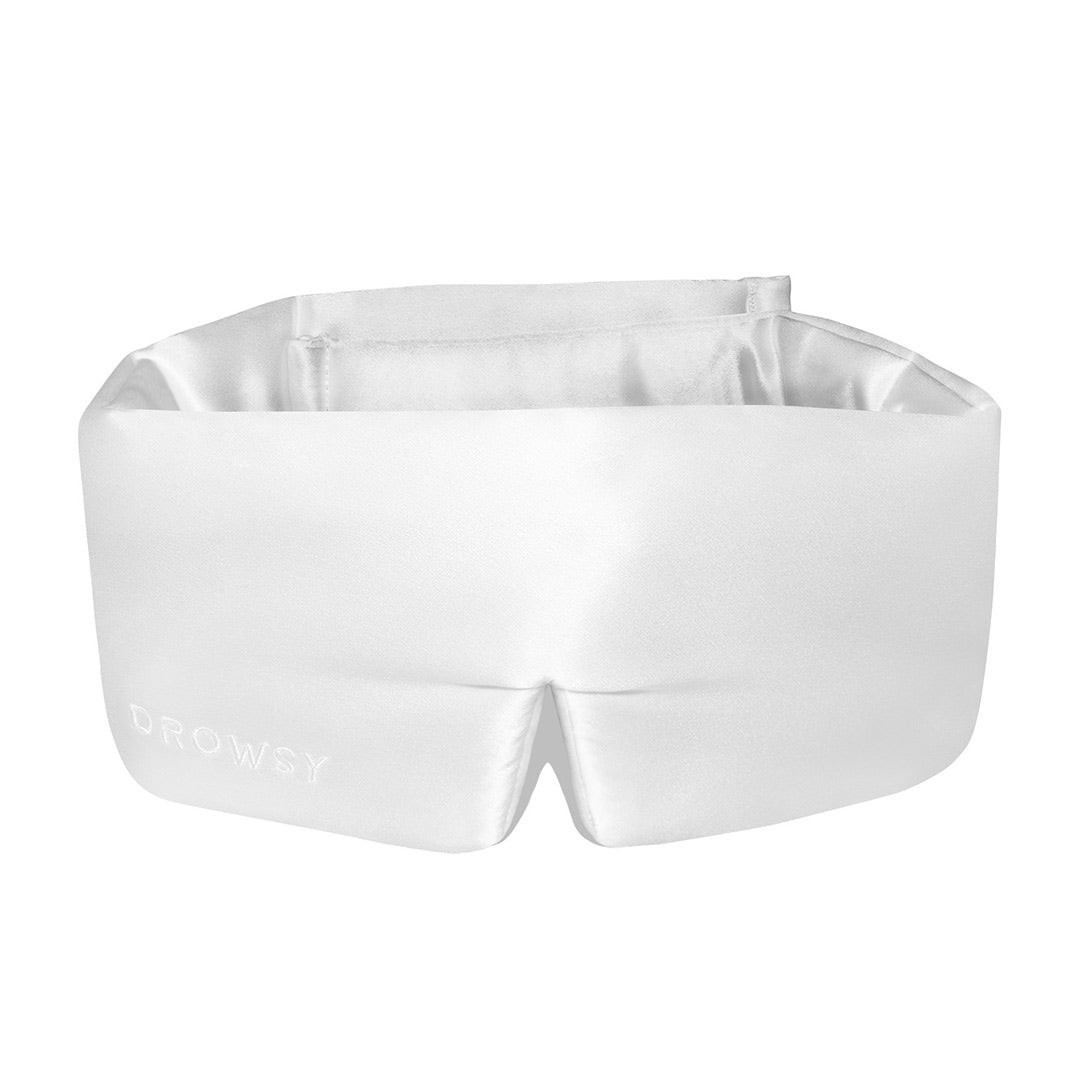 White silk sleep mask with a smooth, shiny finish, featuring a comfortable design and the word "DROWSY" elegantly embroidered on the front.