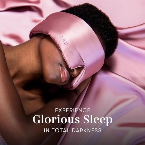 Soft pink satin sleep mask with "DROWSY" embossed, worn by a person resting on a silky surface, promoting a restful sleep experience.