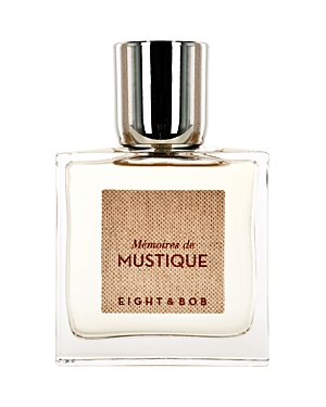 Clear glass bottle with a square shape, featuring a textured beige label that reads "Mémoires de Mustique" and "EIGHT & BOB," topped with a shiny silver cap.