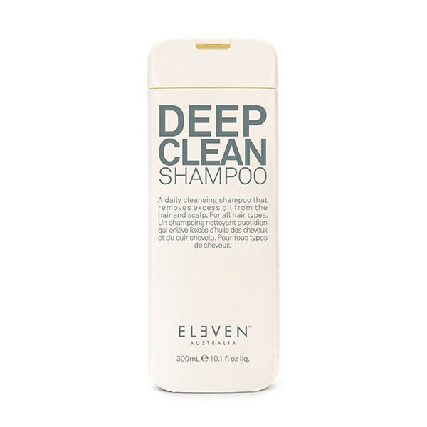 Tall, cream-colored bottle with a flip-top lid, featuring bold blue text that reads "DEEP CLEAN SHAMPOO" and "ELEVEN AUSTRALIA" logo at the bottom, suitable for all hair types.
