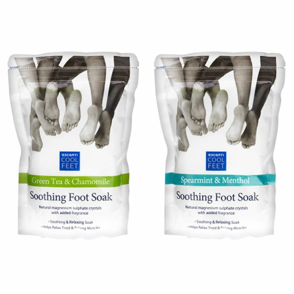 Two packages of Escenti Cool Feet Soothing Foot Soak, one in green tea & chamomile with a green label, and the other in spearmint & menthol with a blue label, both featuring feet graphics.