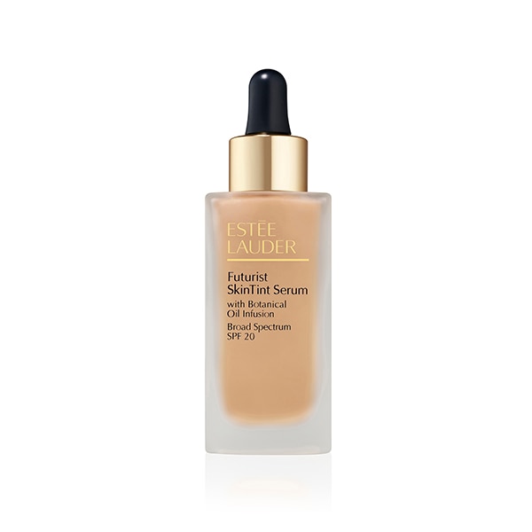 Estee Lauder Futurist SkinTint Serum Foundation in a clear glass bottle with a gold dropper cap, featuring a beige liquid and labeled with black and gold text.