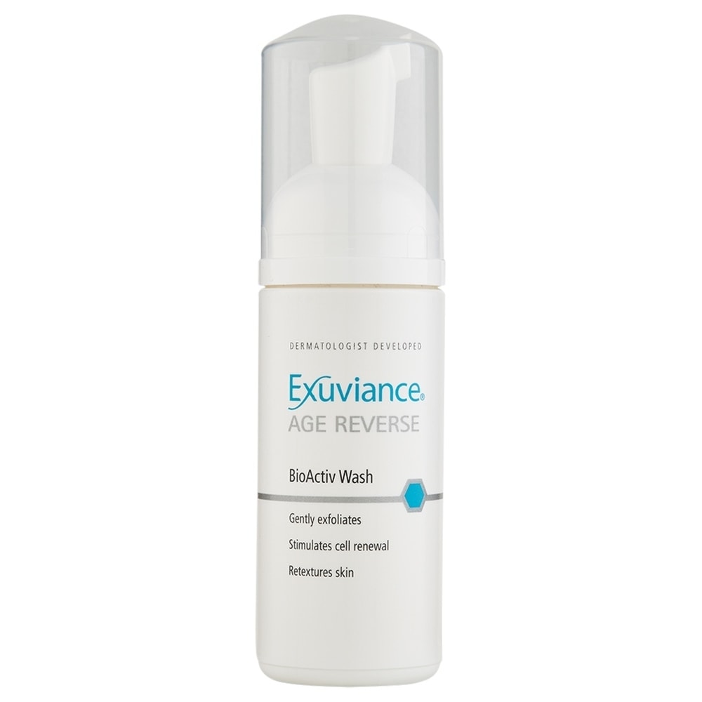 White bottle with a pump dispenser, featuring a clear cap, labeled "Exuviance Age Reverse BioActiv Wash," designed for gentle exfoliation and skin renewal.