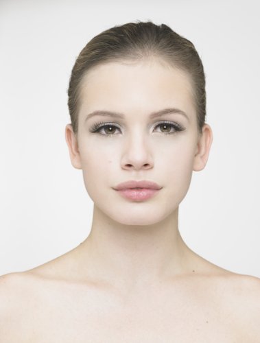 Model with smooth skin and a natural makeup look, featuring subtle eye makeup and long, dark eyelashes, against a plain white background.