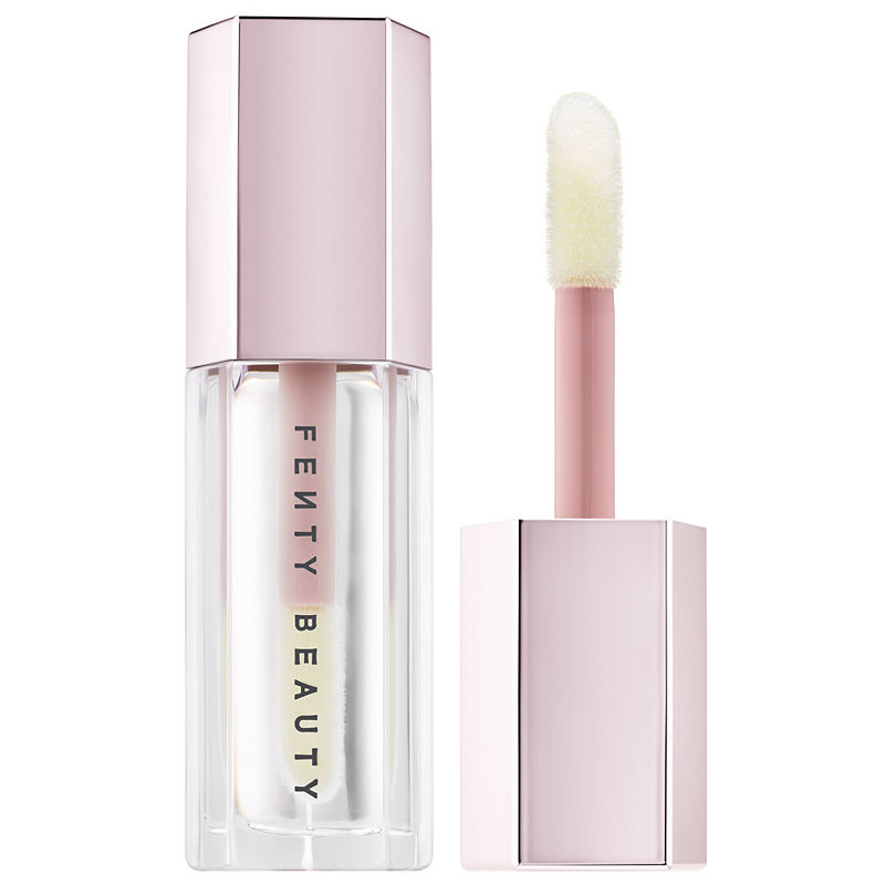 Gloss Bomb Universal Lip Luminizer in a clear tube with a pale pink cap, featuring a doe-foot applicator, showcasing a shimmering, translucent finish.