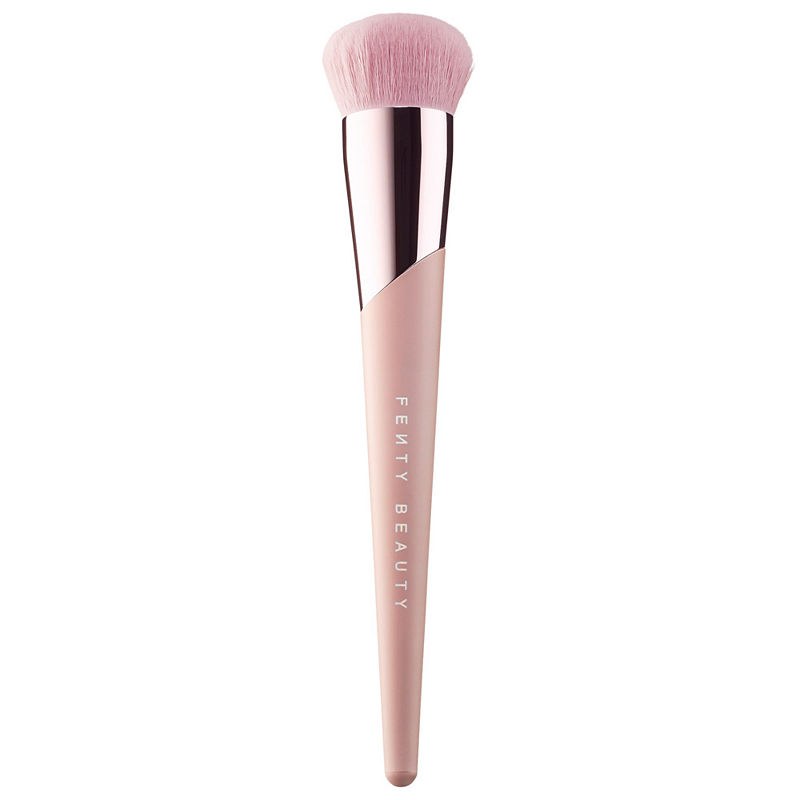 Fenty Beauty Kabuki-Buff Foundation Brush 115 features a tapered handle in soft pink with a glossy silver ferrule and a fluffy, pink bristle head for seamless application.