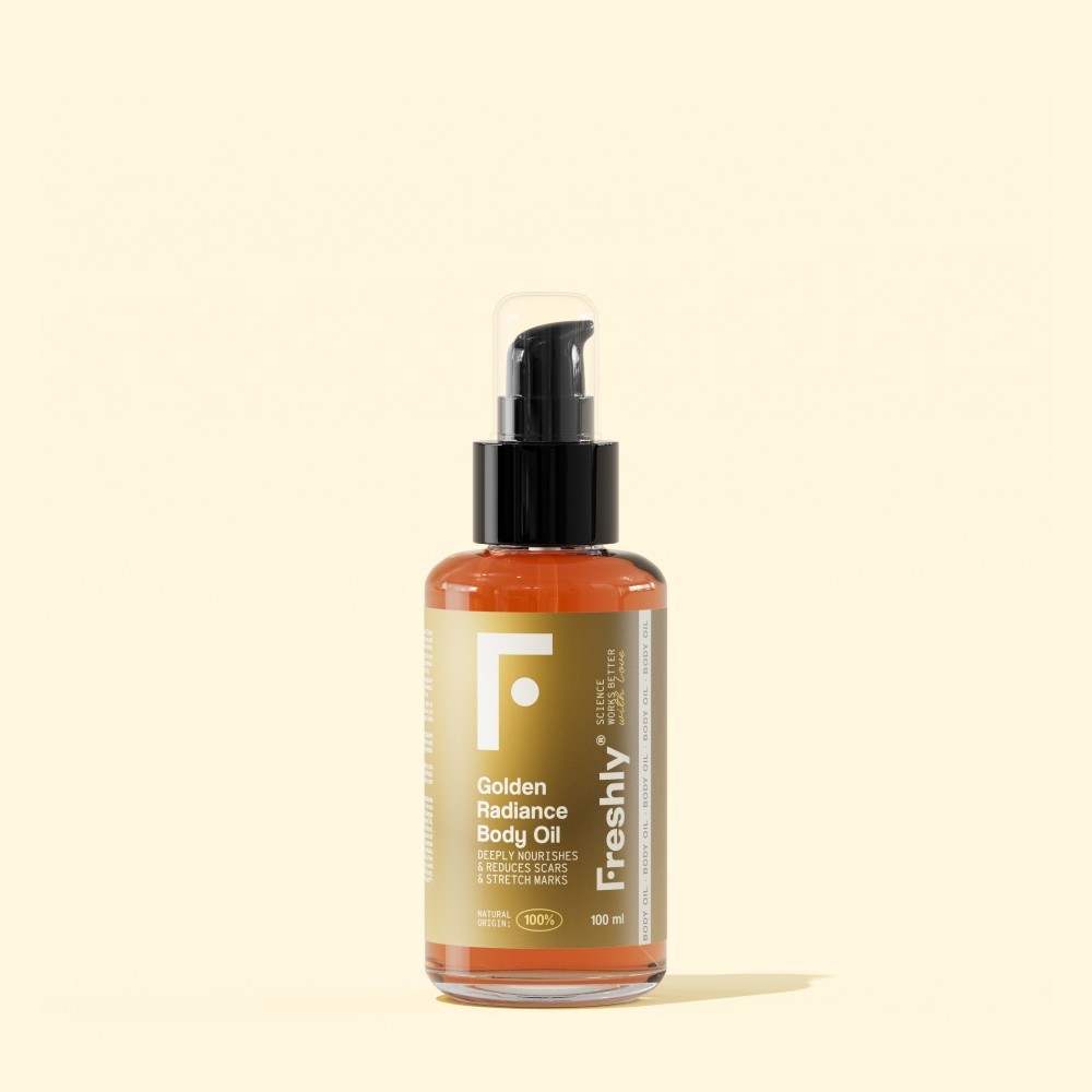 Transparent bottle with a black pump, filled with golden body oil, featuring a white label with black text and a minimalist logo, set against a soft beige background.
